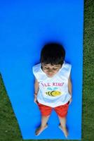 asiatico inteligente ragazzo fare yoga posa nel il società parco all'aperto, figli di yoga posa. il poco ragazzo fare yoga esercizio. foto