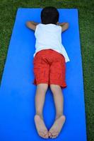 asiatico inteligente ragazzo fare yoga posa nel il società parco all'aperto, figli di yoga posa. il poco ragazzo fare yoga esercizio. foto