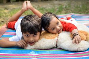 Due contento ragazzi nel società parco, contento asiatico fratelli chi siamo sorridente felicemente insieme. fratelli giocare all'aperto nel estate, migliore gli amici. bambino piccolo bambino ragazzo giocando con il suo contento fratello nel il giardino foto