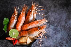 tailandese cibo tom yum kung, caldo e acida speziato gamberetti gamberi la minestra curry Limone lime galangal rosso chili cannuccia fungo su tavolo cibo, gamberetto la minestra su frutti di mare la minestra ciotola con tailandese erba e spezie foto