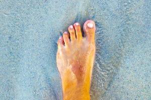 a piedi a piedi nudi su il spiaggia sabbia di il acqua Messico. foto