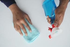 mano in guanti di gomma blu che tengono il flacone spray con copia spazio foto