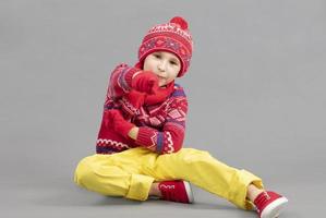 bambino nel caldo a maglia Abiti su un' studio sfondo. un' ragazzo nel un' rosso cappello e maglione. alla moda ragazzo nel il studio. foto