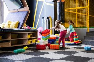 Due sorelle giocando a bambini giocare centro mentre costruire con colorato plastica blocchi. foto