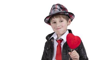 divertente bambino nel un' rosso cravatta e cappello detiene un' bacchetta magica con un' cuore. ragazzo con un' san valentino. foto