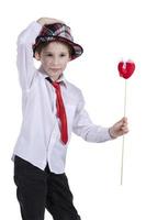 bambino con san valentino. il ragazzo nel il cappello detiene un' rosso cuore. bellissimo alla moda bambino. foto