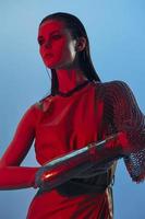 giovane donna fascino in posa rosso leggero metallo armatura su mano isolato sfondo foto