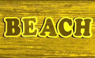 parola spiaggia su giallo legna sfondo foto