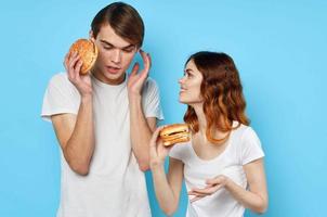 donna e uomo nel bianca magliette veloce cibo dieta blu sfondo foto