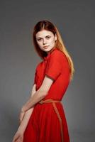 dai capelli rossi donna nel rosso vestito in posa attraente Guarda isolato sfondo foto