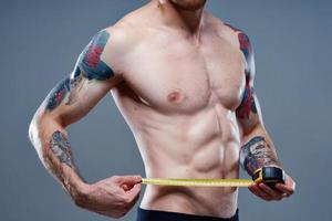 atleta con pompato su braccio muscoli e tatuaggi bodybuilder fitness centimetro nastro foto