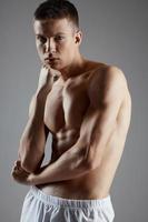 bello sportivo con nudo torso su grigio sfondo e bicipite bodybuilder fitness foto