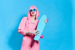 alla moda donna con skateboard nel rosa parrucca isolato sfondo foto