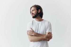 ritratto di un' triste uomo con un' nero di spessore barba e lungo capelli nel un' bianca maglietta su un' bianca isolato sfondo foto