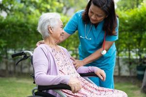medico Aiuto e cura asiatico anziano donna paziente seduta su sedia a rotelle a parco nel assistenza infermieristica ospedale reparto, salutare forte medico concetto. foto