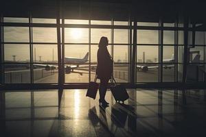 viaggio concetto, persone nel il aeroporti ,silhouette di giovane ragazza con bagaglio a piedi a aeroporto, donne mostrando qualcosa attraverso il finestra,selettivo messa a fuoco, vintage tono colore foto