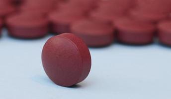 uno rosso marrone medico pillola avvicinamento su un' blu sfondo e su il sfondo di un' mucchio di pillole. foto