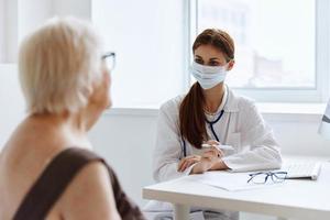 anziano donna indossare un' medico maschera comunica con il medico Salute cura foto