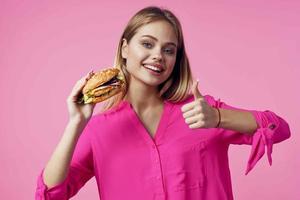 allegro bionda nel un' rosa camicia Hamburger veloce cibo merenda foto