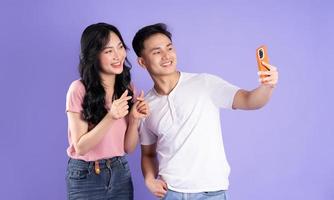 Immagine di asiatico coppia Tenere smartphone, isolato su viola sfondo foto