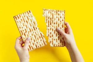 donna è Tenere matzà. festeggiare il tradizionale ebraico vacanza di Pasqua ebraica o pesach. pane azzimo su un' giallo sfondo. foto