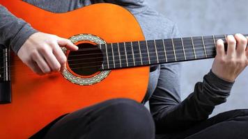 ragazza suona una chitarra acustica di colore arancione su sfondo grigio foto