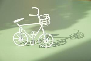 decorativo bianca bicicletta su verde sfondo con difficile ombre. sostenibile stile di vita concetto foto