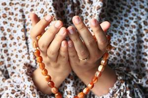 mani della donna che pregano con perline
