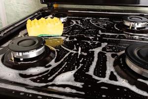 pulire la cucina lavando la superficie con schiuma e un panno giallo foto