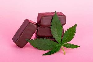 caramelle al cioccolato con cannabis medica su sfondo rosa foto