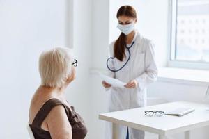 vecchio donna paziente su visita medica di un' infermiera medico ufficio foto