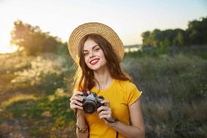 donna nel un' cappello con un' telecamera nel sua mani rosso labbra attraente Guarda natura foto