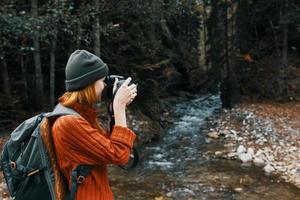 donna con un' telecamera su natura nel il montagne vicino il fiume lato Visualizza foto