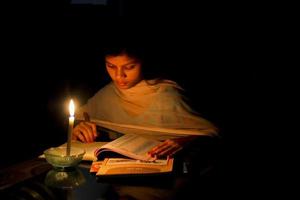 un' giovane ragazza studiando a casa con lume di candela dopo elettricità caricare muta a dhaka città. foto