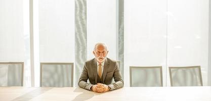 anziano attività commerciale uomo seduta nel il sala del consiglio a il ufficio foto