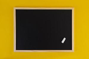 lavagna nera vuota su sfondo giallo. vista frontale sulla lavagna nera con cornice in legno. copia spazio vuoto su schermo piatto.
