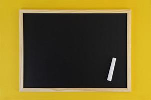 lavagna nera vuota su sfondo giallo. vista frontale sulla lavagna nera con cornice in legno. copia spazio vuoto su schermo piatto.