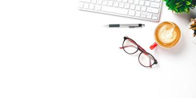 ufficio scrivania con tastiera del computer, penna, occhiali, tazza di caffè su bianca sfondo, superiore Visualizza con copia spazio, finto su. foto