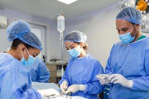 preparazione per il inizio di chirurgico operazione con un' tagliare. gruppo di chirurghi a opera nel operativo Teatro tonica nel blu. medico squadra l'esecuzione operazione foto