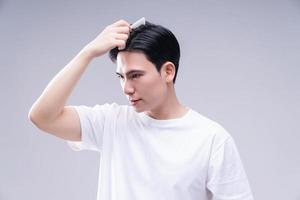 Immagine di giovane asiatico uomo capelli cura su sfondo foto