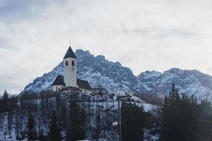 Chiesa su neve montagna con cielo nel sfondo foto