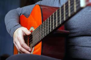 ragazza suona una chitarra acustica arancione con corde di nylon