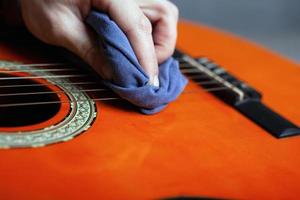 pulire il corpo della chitarra acustica con uno straccio pulito foto