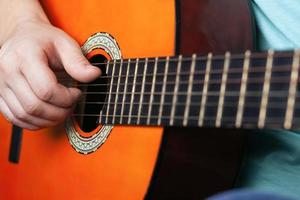 mano maschile suona corde di chitarra acustica foto