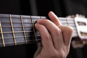 mano maschile blocca un accordo di chitarra acustica