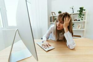 scioccato bionda donna d'affari fatto grande sbaglio nel rapporto Guarda a schermo reclinare su mano seduta a posto di lavoro nel moderno ufficio. infelice dipendente opera su computer in linea nel supporto servizio. largo angolo foto