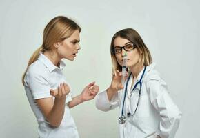 un oltraggiato paziente comunica con un' infermiera nel un' medico toga e un' siringa nel sua mano foto