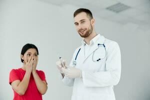 maschio medico Tenere un' siringa nel il suo mani il paziente è impaurito di covid vaccinazione foto