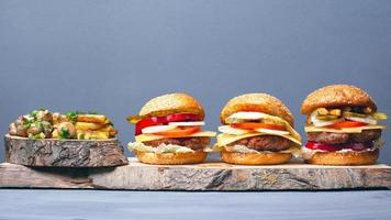 tre gustosi hamburger assortiti con patatine fritte e funghi su uno sfondo grigio