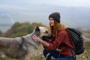 donna escursionista con un' zaino passeggiate il cane nel il montagne nel natura foto